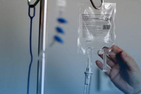 Рука тянется к пакету капельницы